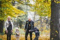 Photo of happy family in autumn park, parents with cheerful babies playing in fall forest