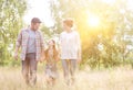 Happy family walking in wheat field with yellow lens flare in background Royalty Free Stock Photo