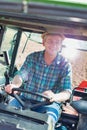 Happy farmer driving tractor in field