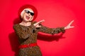 Photo of happy funky cheerful old woman wear cool sunglass hat dancer isolated on red color background