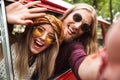 Photo of happy hippie travelers man and woman smiling, and sitting in retro minivan in forest Royalty Free Stock Photo