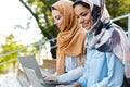 Photo of happy islamic girls wearing headscarfs studying in park