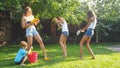 Photo of happy laughing family splashing water with water guns and garden hose at backyard. People playing and having Royalty Free Stock Photo