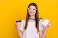 Photo of happy lovely woman good mood look copyspace hold coffee wear tag isolated on yellow color background