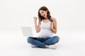 Happy pregnant woman holding debit card winking using laptop Royalty Free Stock Photo