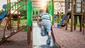 Image of happy smiling cheerful toddler boy riding and climbing on the big children playground at park Royalty Free Stock Photo