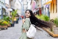 Photo of happy smiling Indian young girl walking, running looking back down city street, holding backpack and wind Royalty Free Stock Photo