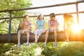 Happy teenage boys and girls sitting on wooden bridge Royalty Free Stock Photo