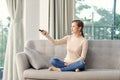 Photo of happy young woman sitting on sofa at home. Looking camera holding remote control watch TV Royalty Free Stock Photo