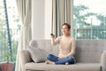 Photo of happy young woman sitting on sofa at home. Looking camera holding remote control watch TV Royalty Free Stock Photo