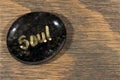 Healing stone with painted soul word on wooden background