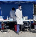 Medical Technician giving Covid shots outside wearing a face mask and Lab coat