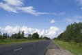 Road in the north of Russia stretches into the distance on a clear summer day