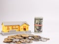 Photo of house miniature with dollar bills and coins isolated on white background. Royalty Free Stock Photo