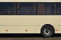 Photo of the hull of a large and long yellow bus with free space for advertising. Close-up side view of a passenger vehicle for t