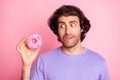 Photo of hungry addicted young man look hold doughnut lick lip isolated on shine pink color background