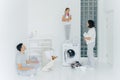 Photo of husband and wife, their dog and daughter do housework in laundry room, little girl stands with detergent on top of Royalty Free Stock Photo