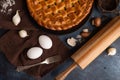 The photo illustrates homemade pie with mushrooms isolated on dark background. The brown napkin, two eggs. garlic, fork, rolling Royalty Free Stock Photo