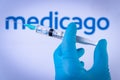 In this photo illustration a hand in medical gloves hold a syringe in front of Medicago logo in Barcelona, Spain on September 2, 2