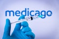 In this photo illustration a hand in medical gloves hold a syringe in front of Medicago logo in Barcelona, Spain on September 2, 2