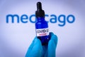 In this photo illustration a hand in medical gloves hold a syringe in front of Medicago logo in Barcelona, Spain on September 2, 2