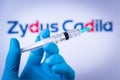 In this photo illustration a hand in medical gloves hold a syringe in front of Zydus Cadila logo in Barcelona, Spain on September