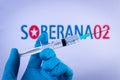 In this photo illustration a hand in medical gloves holds a syringe in front of Soberana 02 vaccine logo in Barcelona, Spain on Se