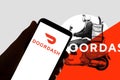 In this photo illustration the logo of the food delivery service Doordash is seen on the screen of mobile phone and of a laptop in