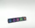 Photo Illustration, Word Sorry from black plastic alphabet cube beads