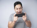 Funny Young Asian Guy Playing Games on Tablet