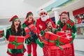 Photo of impressed amazed santa claus assistants wear costumes smiling riding cart buying many gift packages indoors