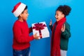 Photo of impressed funky dark skin children wear pullover headwear scarf giving present isolated blue color background