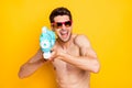 Photo of impressed funky young guy shirtless arm dark glasses smiling shooting water gun isolated yellow color