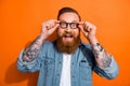 Photo of impressed funny man wear jeans shirt arms spectacles open mouth isolated orange color background