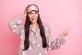 Photo of impressed funny young woman dotted sleepwear mask arm head pointing finger empty space isolated pink color