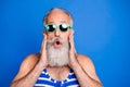 Photo of impressed grey beard man hands face wear eyewear blue swimsuit isolated on blue background Royalty Free Stock Photo