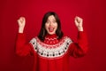 Photo of impressed lucky girl dressed x-mas ornament pullover rising fists screaming isolated red color background Royalty Free Stock Photo