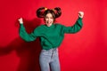 Photo of impressed lucky young woman dressed green knitted sweater rising fists isolated red color background