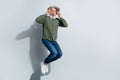 Photo of impressed man pensioner dressed khaki shirt arms hands spectacles jumping high isolated grey color background