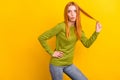 Photo of impressed orange millennial lady hold hair wear green sweater isolated on yellow color background Royalty Free Stock Photo