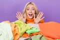 Photo of impressed overjoyed girl raise opened arms palms behind pile stack clothes isolated on violet color background