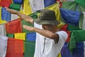 Photo of a Indian young guy making Dab gesture with his hands, posing against tibetan buddhist prayer flags
