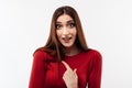 Photo of indignant brunette female in casual red sweater pointing finger at herself. Studio shot, white background