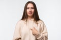 Photo of indignant brunette woman with long straight hair, points at herself with for finger