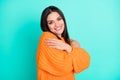 Photo of inspired tender woman embrace herself wear orange sweater  turquoise color background Royalty Free Stock Photo