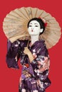 Portrait of Japanese woman in kimono holding parasol against red background Royalty Free Stock Photo