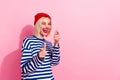 Photo of joking young girl wear red beanie headwear fingers directing you blinking eye advert poster isolated on pink