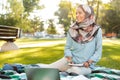 Photo of joyful arabic woman wearing headscarf writing down notes in notebook