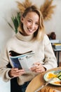 Photo of joyful blonde woman reading magazine while having breakfast Royalty Free Stock Photo