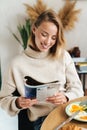 Photo of joyful blonde woman reading magazine while having breakfast Royalty Free Stock Photo